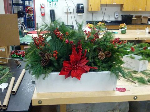 Holiday planter stuffed with stems of evergreen and both natural and artificial accents.