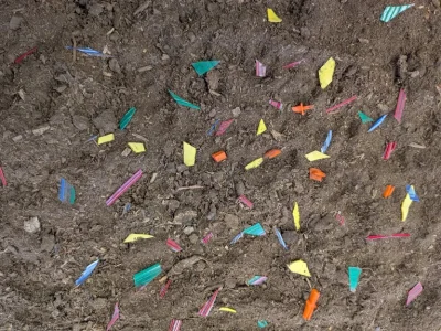 Colorful plastic fragments scattered across dark soil.