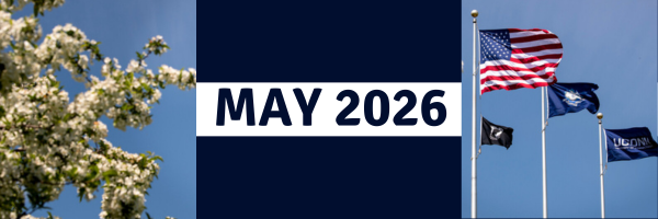 Banner reading “May 2026” centered on a dark blue panel, flanked by white spring blossoms against a blue sky on the left and three flagpoles on the right displaying the U.S. flag, a POW/MIA flag, and a UConn flag